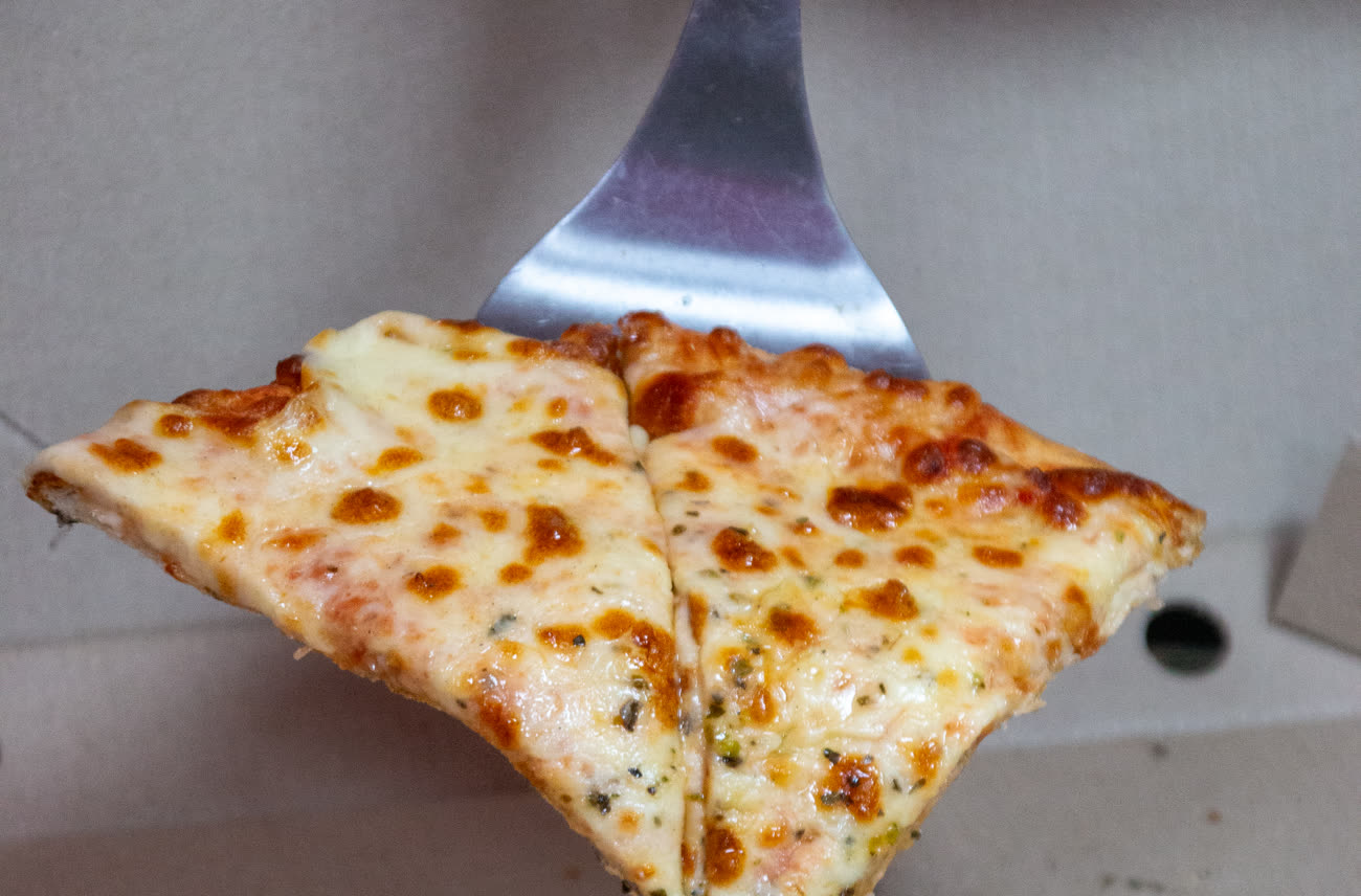 A slice of woodfired cheese pizza lifted from the box